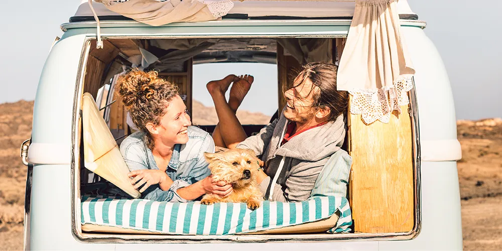 Couple relaxing inside a caravan with their small dog while travelling through the Australian outback